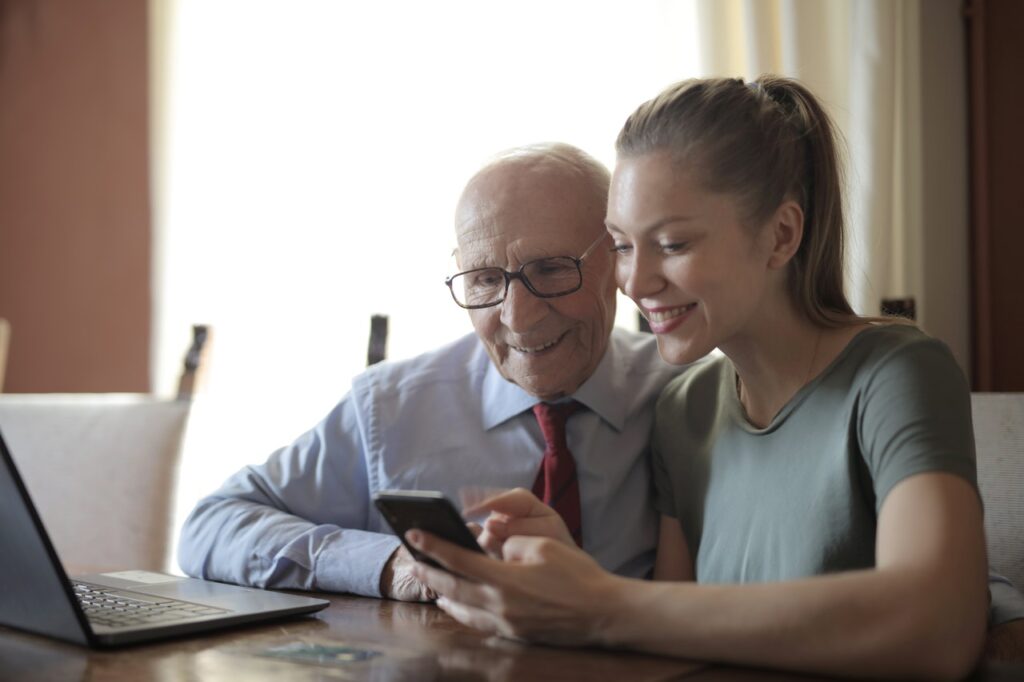 młoda kobieta pokazuje smartfon seniorowi